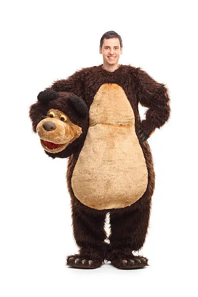 Full length portrait of a young man in a bear costume smiling and looking at the camera isolated on white background