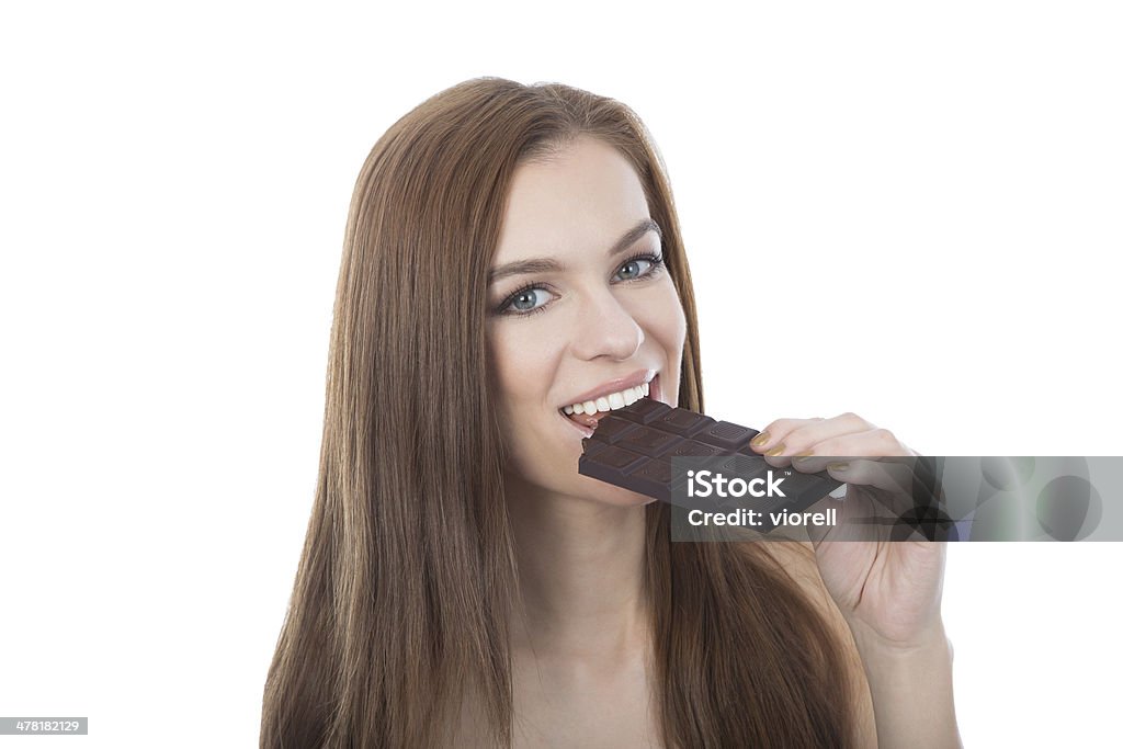 Woman biting a chocolate bar. Closeup isolated on white backgrou A beautiful woman biting a dark chocolate bar. A closeup isolated on a white background Adult Stock Photo
