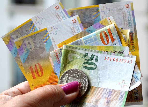 Swiss currency Human hand holding a stack of Swiss Francs, banknotes and coins. french currency photos stock pictures, royalty-free photos & images