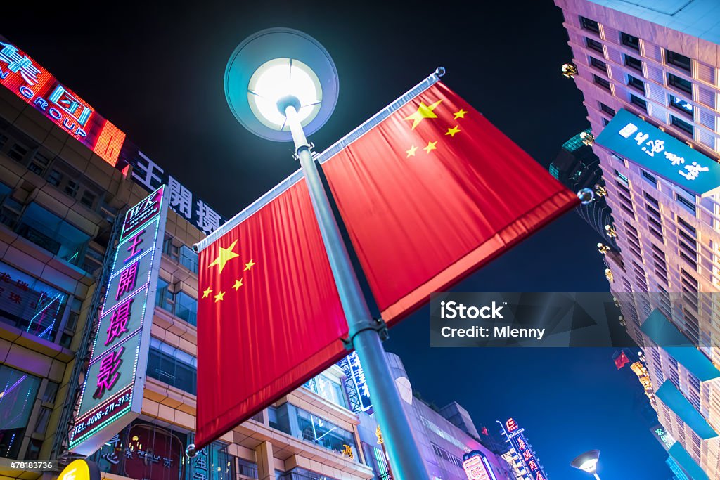 China Flag Shanghai Nanjing Road Chinese Power Symbol Glowing chinese flag from below towards the night sky in the famous Nanjing Shopping Road in Shanghai. Shot from a dramatic extreme wide angle perspective as an iconic - symbolic image to strive out the chinese power, Nanjing Road, Shanghai, China. 2015 Stock Photo
