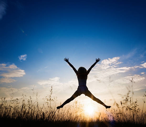 istock Female silhouette jumping in the air at sunset 478192006