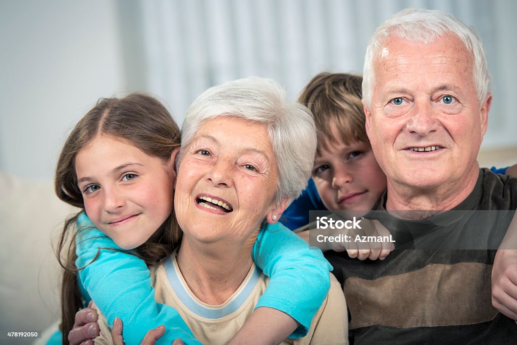 Portrait with Grandparents Portrait of two children with their grandparents. Children are behind them and are hugging them. They are looking at camera, smiling. 2015 Stock Photo