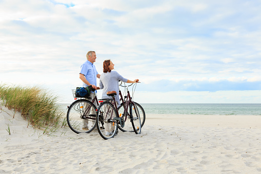 Active mature couple with bikes on the beach