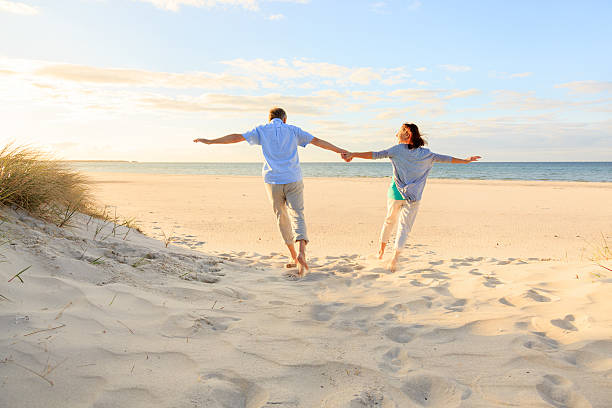 Happy mature couple outdoors on the beach Active mature couple running on the beach baltic sea people stock pictures, royalty-free photos & images