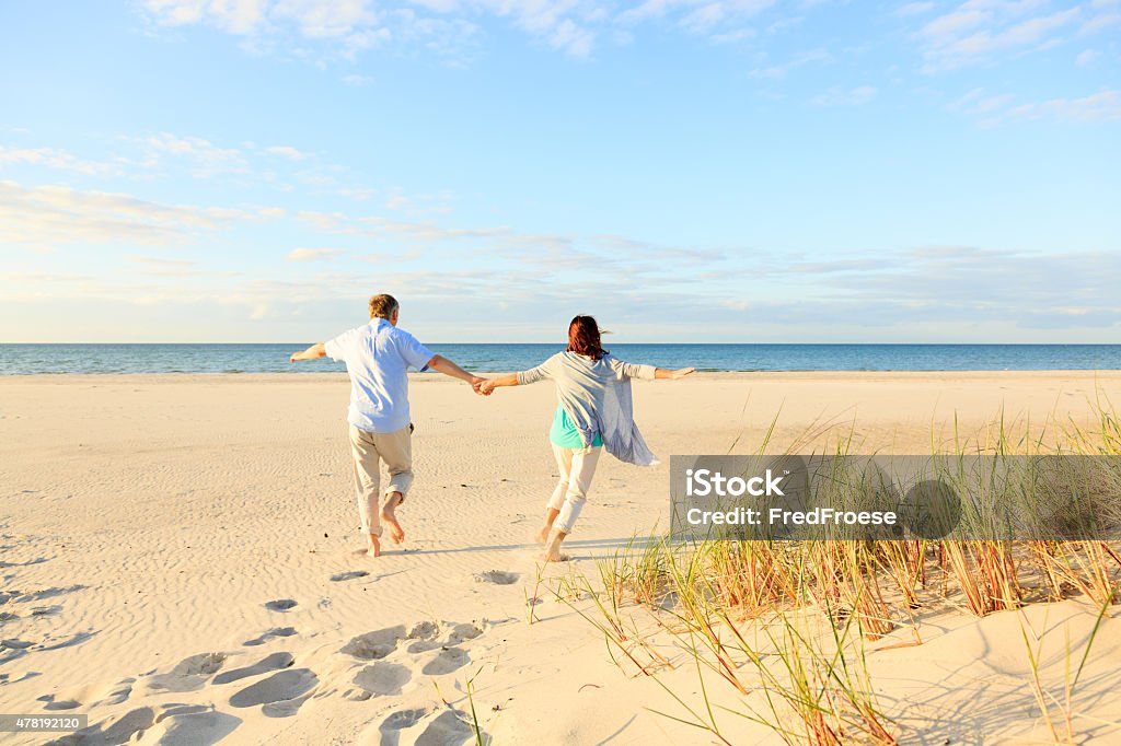 Happy mature couple outdoors on the beach Active mature couple running on the beach 2015 Stock Photo