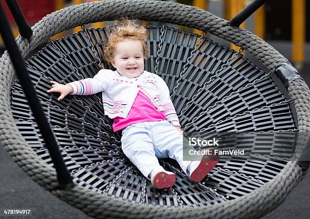 Cute Laughing Baby Girl At Net Swing On The Playground Stock Photo - Download Image Now