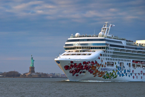 New York, NY, USA - March 08, 2014: Norwegian Gem sailing by the Statue of Liberty.