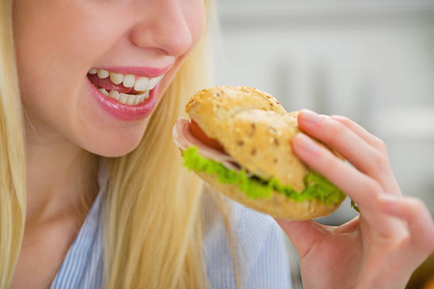 istock closeup on young woman eating sandwich 478198551