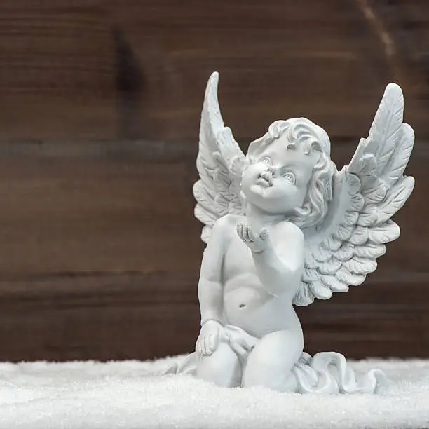 Photo of little white guardian angel in snow. christmas decoration