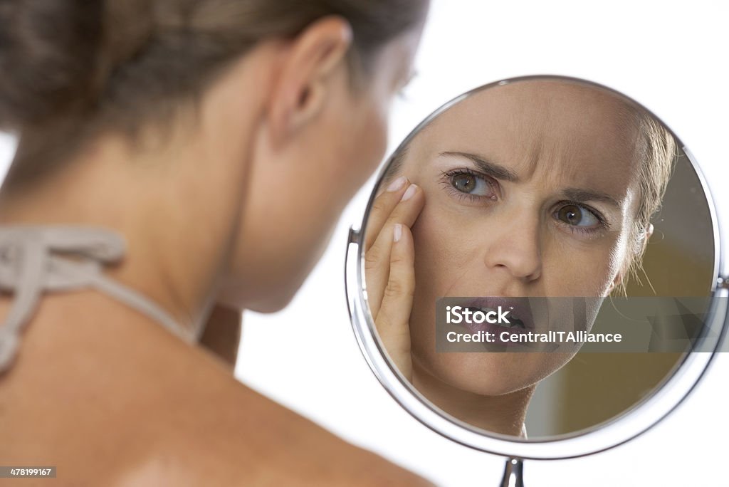 concerned young woman looking in mirror Concerned young woman looking in mirror Mirror - Object Stock Photo