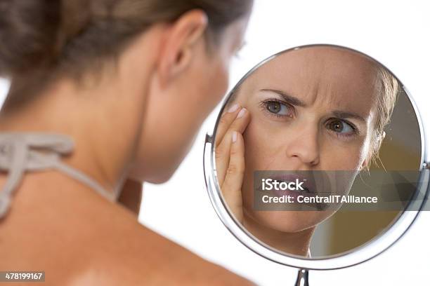 Concerned Young Woman Looking In Mirror Stock Photo - Download Image Now - Mirror - Object, Aging Process, Women