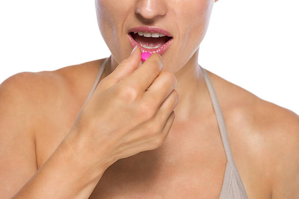 istock closeup on young woman eating pill 478199343