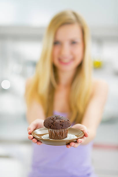istock closeup on young woman showing chocolate muffin 478199393