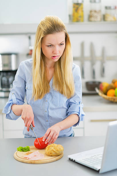 istock young woman making snacks and looking on laptop 478199399