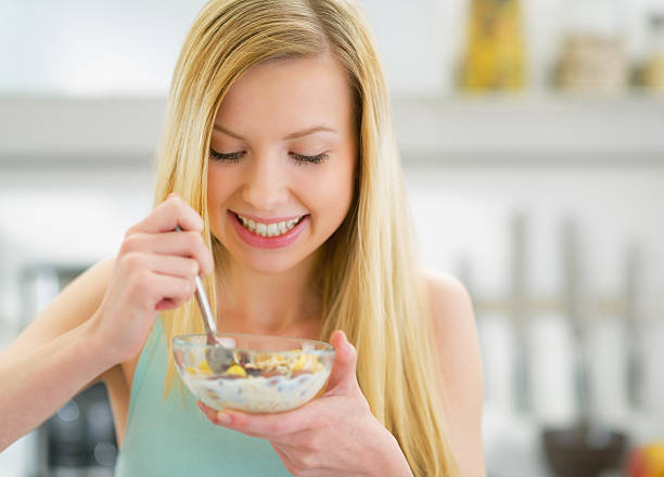 istock happy young woman eating muesli in kitchen 478199659