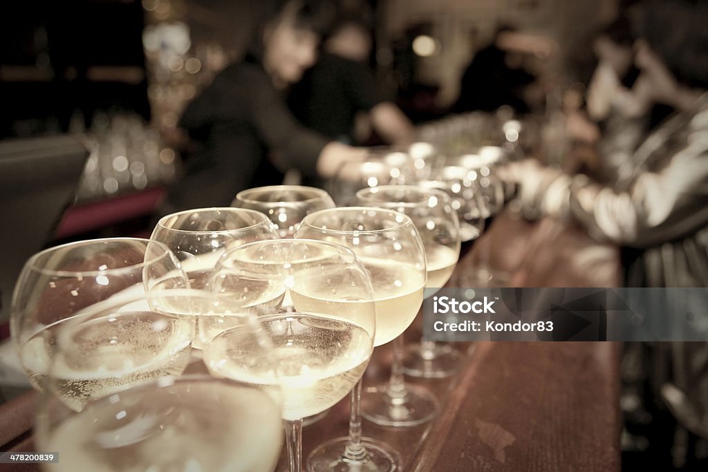 Wineglasses on bar counter Wineglasses on bar counter with blurred crowd in background Auto Post Production Filter Stock Photo