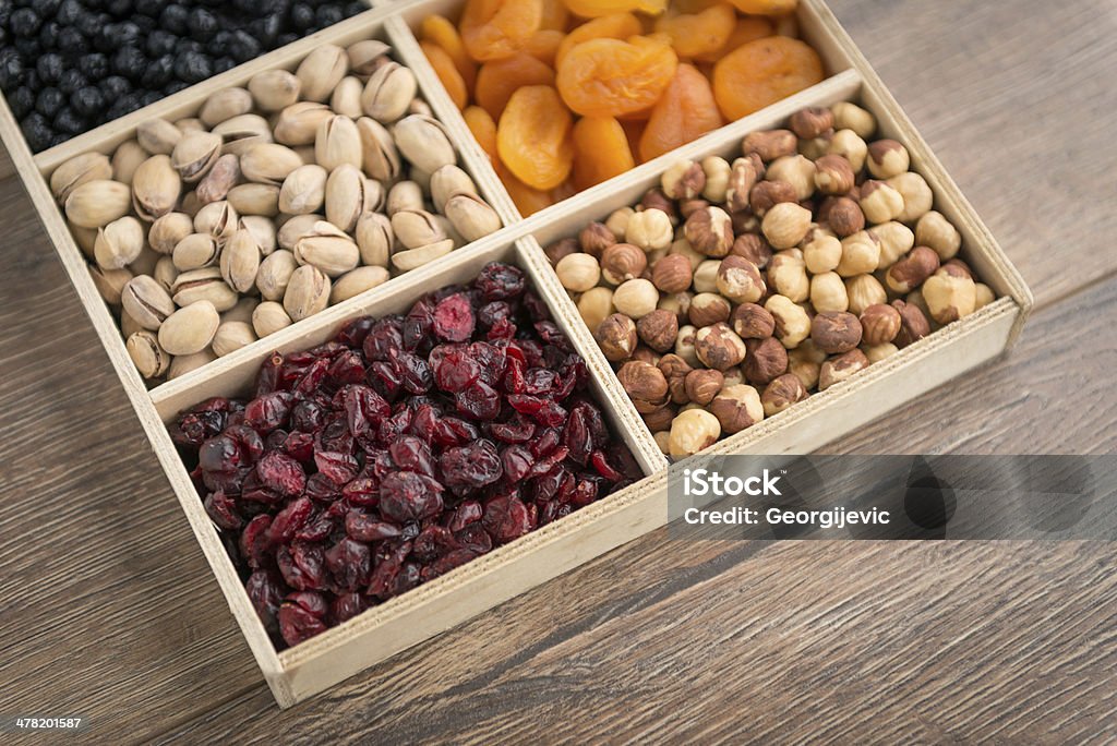 Nuts and dried fruits. Hazelnuts, almonds, cranberries, pistachios, dried apricots and chokeberries in wooden bowl. Almond Stock Photo