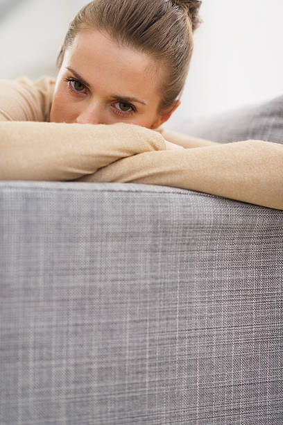 istock stressed young woman sitting on couch 478208545