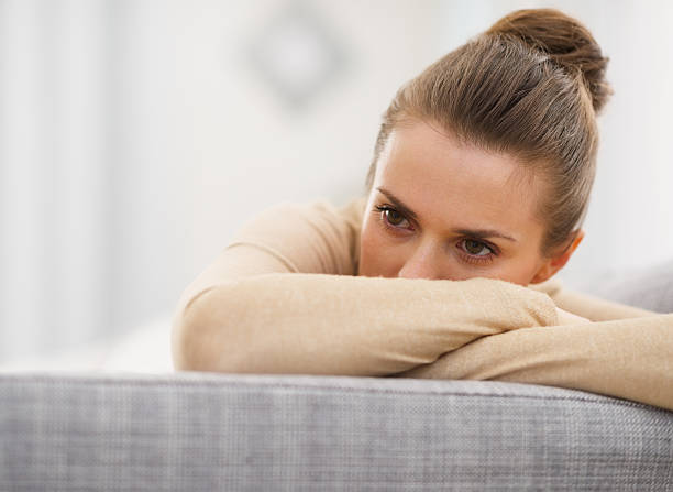 stressed young woman sitting on sofa stock photo