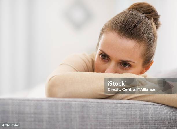 Stressed Young Woman Sitting On Sofa Stock Photo - Download Image Now - Women, Sadness, Depression - Sadness
