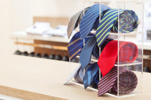 set of rolled up neck ties on plastic shelf in a shop