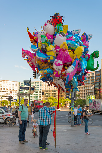 Berlin, Germany - June 11, 2015: A seller with a lot of colorful balloons standing at the Potsdamer Platz in Berlin, Germany. Some people and children looking at them. 