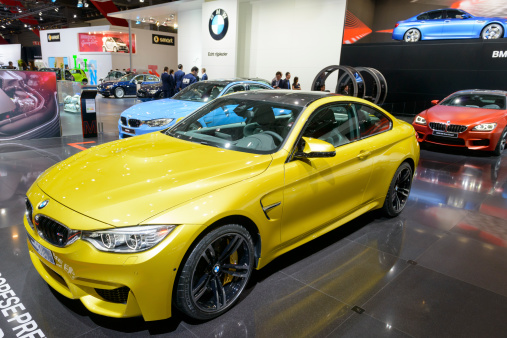 Brussels, Belgium - January 14, 2014: BMW M4 coupe sports car with the BMW M3, M5 and M6 Gran Coupe on display at the 2014 Brussels motor show. The M4 is the M Performance version of the BMW 4-series. People in the background are looking at the cars.