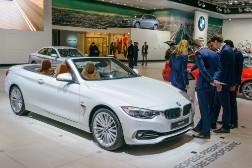 Brussels, Belgium - January 14, 2014: BMW 4 Series Convertible 428i on display during the 2014 Brussels motor show. A group of people is looking at the car while other people in the background are talking and looking at the cars.