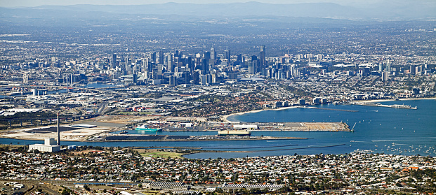 Aerial panorama of Melbourne city, port and surrounding suburbs – view from light aircraft.  Shows Webb Dock Yarra River, Newport Power Station, Newport Railway Workshops, Bolte Bridge, Rialto building, Melbourne Eye, MCG, sporting stadiums, freeways.  Horizontal, panorama format, some vibration movement.