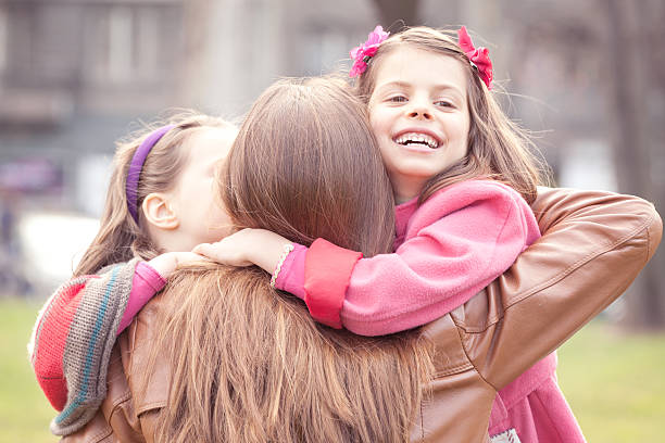 Two Happy Daughters Embracing their Mother Two Happy Daughters Embracing their Mother in the Spring Day . three way kiss stock pictures, royalty-free photos & images