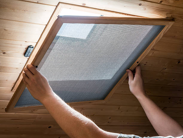 Installing homemade mosquito net on velux window on ceiling stock photo