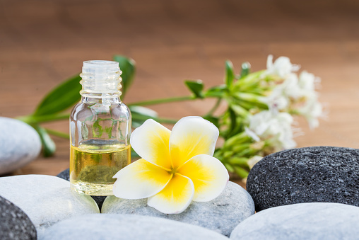 Essential Oil and flower on pebble stone with blur background glass bottle