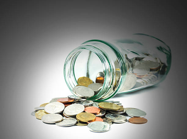 istock Coins spilling out of a glass bottle 478227062