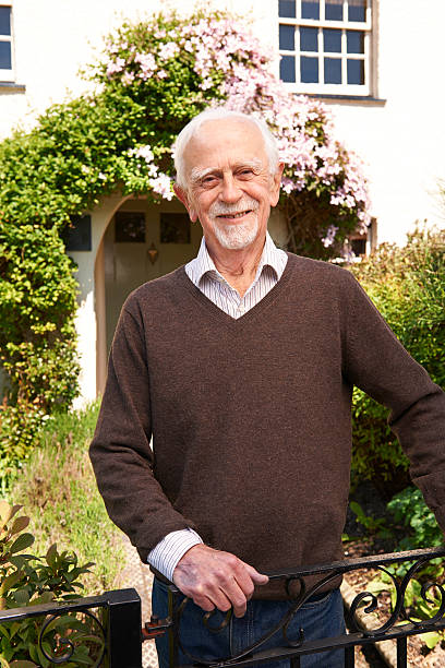 istock Senior Man Standing Outside Pretty Cottage 478231196