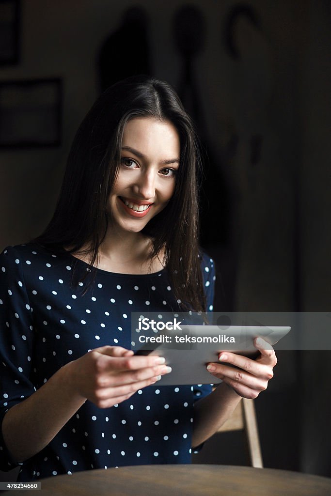 Beautiful girl working on a tablet and smiling Beautiful girl working with high technology and a smile 2015 Stock Photo