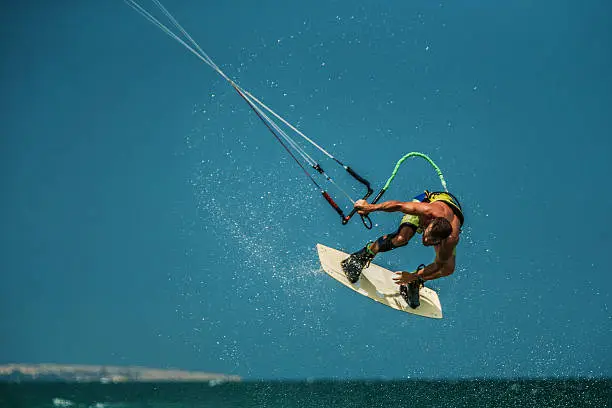 Handsome man Kitesurfing in blue sea