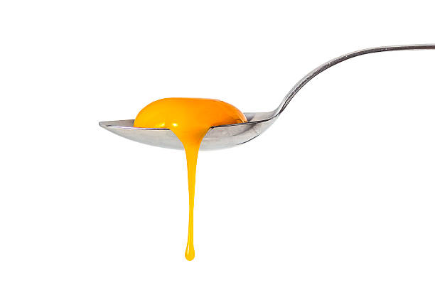 Egg yolk leaking from the spoon Raw egg yolk leaking from the spoon, isolated on white egg yolk stock pictures, royalty-free photos & images