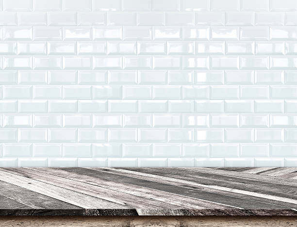 istock Empty Diagonal Wooden Table top at blurred white tiles wall 478239298