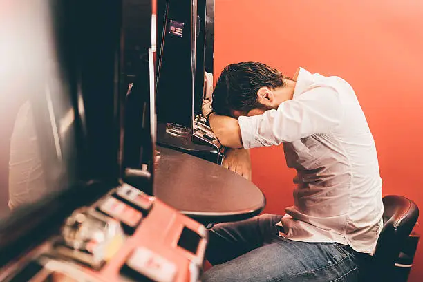 man just loosing at the slot machine, being sad