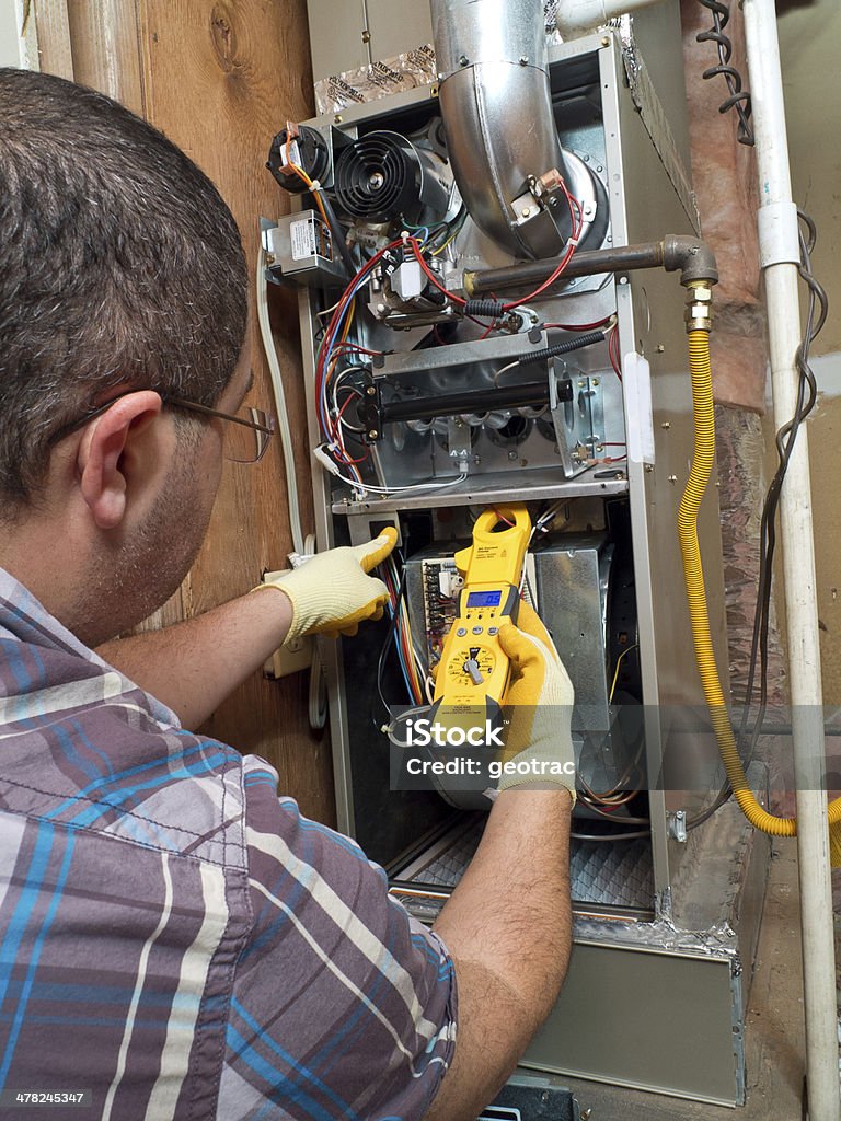 Hispanic handyman repairman conducting residential HVAC repair Furnace Stock Photo