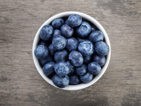 fresh blueberries in white bowl on wood table, rustic style