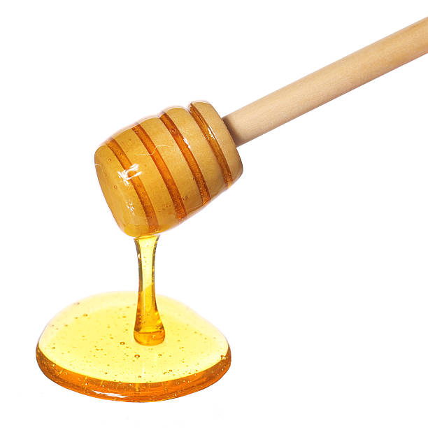 istock Honey dripping from wooden honey dipper isolated on white 478247777