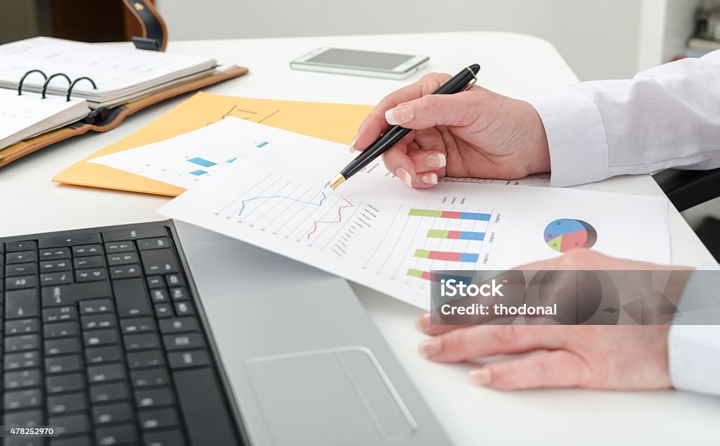 Businesswoman working on financial graphs Businesswoman working on financial graphs at the office 2015 Stock Photo