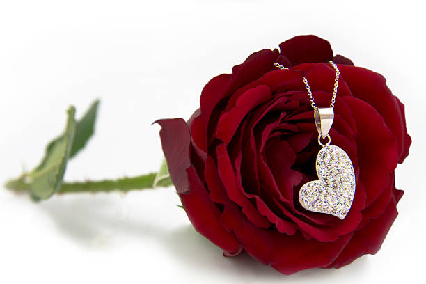 Broken red heart necklace on wooden background. Two parts of the heart.