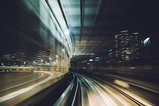 Tokyo subway tracks seen into the tunnel in movement. The view of contemporary and modern tunel construction with window. Through the  window is visible the city and the road.