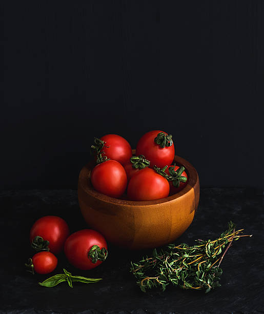Ripe cherry-tomatoes in wooden bowl with basil leaves