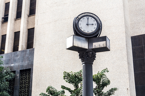 railway station display with analog clock and modern silver metal architecture in blurred background as concept for train travel train announcements and delays