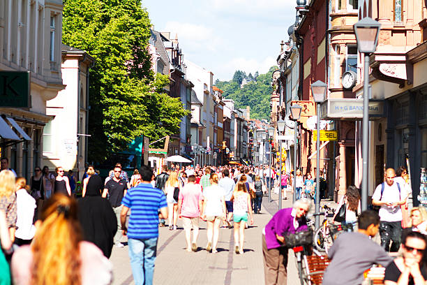 Many shopping people in Heidelberg at summer View along main shopping street and pedestrian zone Hauptstraße in Heidelberg in summer. Sunny day, No focus on people in foreground. Non editorial crowd shot with multiple logos in background area. Crowd of people different ethnicities is walking in street. heidelberg germany stock pictures, royalty-free photos & images