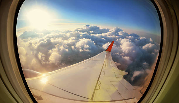 nuvole e cielo visto attraverso una finestra di aerei - wing airplane window sunset foto e immagini stock