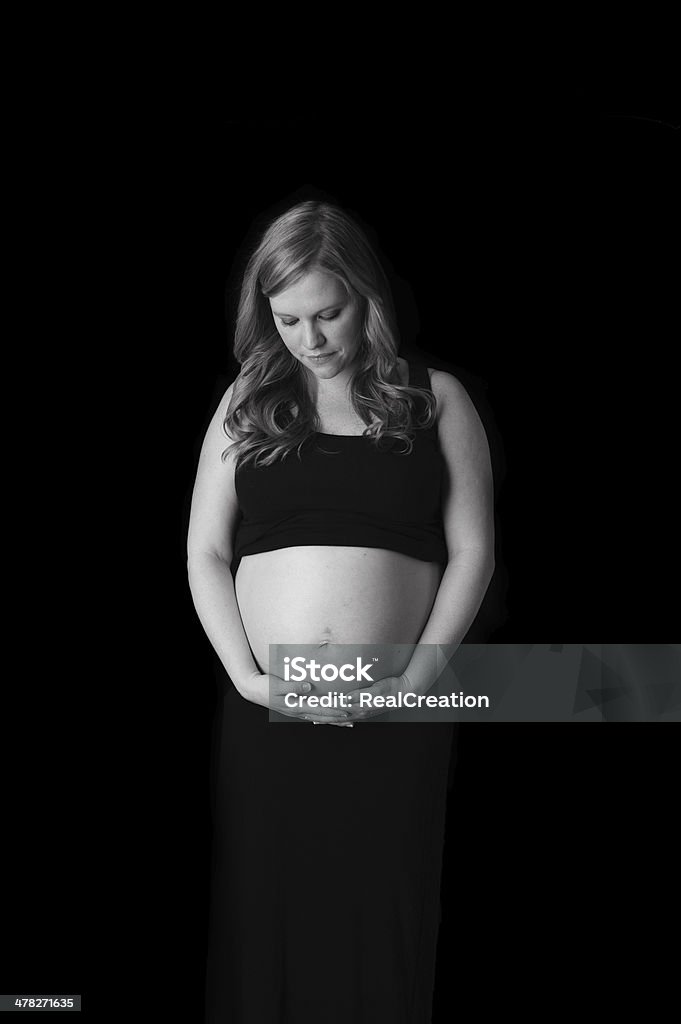 Kobieta w ciąży Patrząc na brzuch - Zbiór zdjęć royalty-free (Antycypacja)